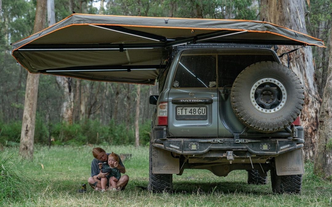 DARCHE freestanding awning set up at a remote bush campsite alongside camping chairs and a table, showing the full coverage area in use